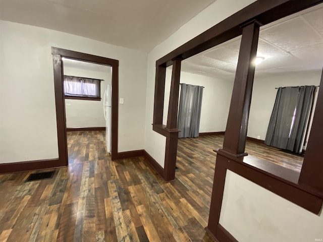 hallway with baseboards, visible vents, and wood-type flooring