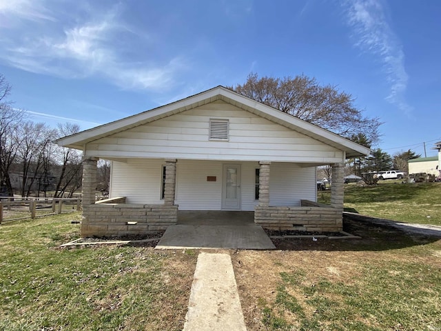 bungalow with covered porch and a front lawn