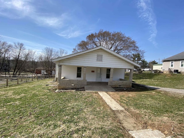 bungalow-style house featuring covered porch, a front lawn, and fence