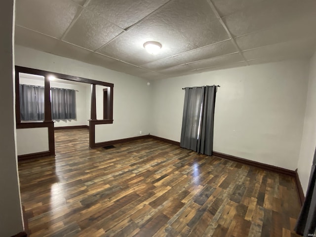 spare room with baseboards and wood finished floors