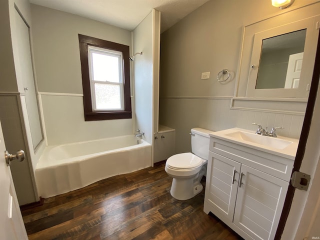 bathroom featuring a wainscoted wall, toilet, wood finished floors, tile walls, and vanity