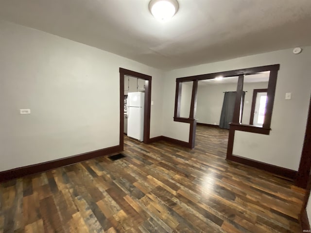 empty room featuring dark wood finished floors, baseboards, and visible vents