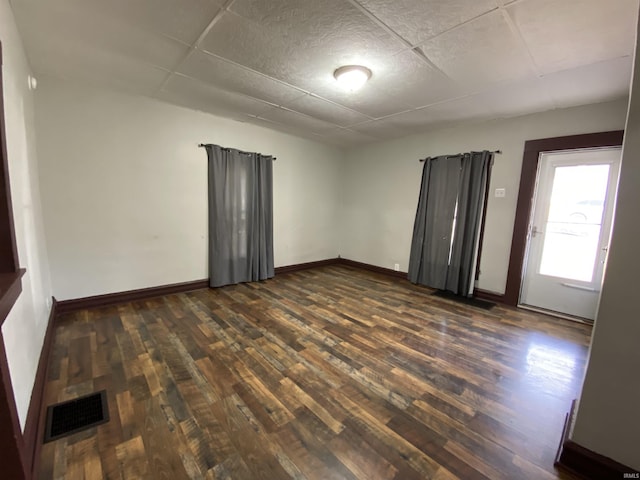 spare room with visible vents, baseboards, and dark wood-type flooring