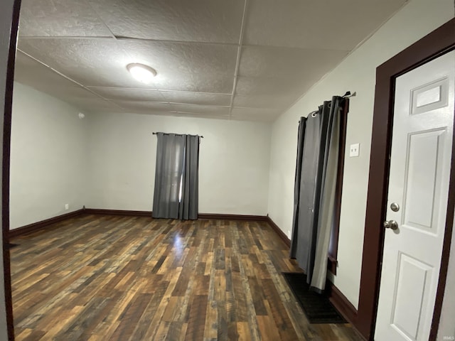 empty room with a paneled ceiling, baseboards, and wood-type flooring