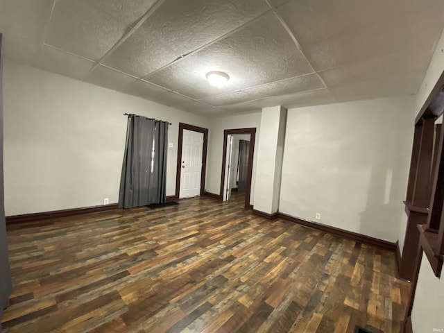 unfurnished bedroom with dark wood-type flooring, baseboards, and a drop ceiling