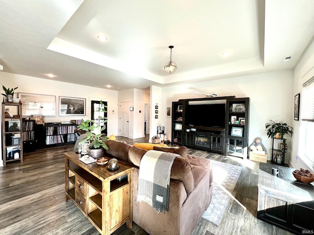 living room featuring visible vents, a tray ceiling, and wood finished floors