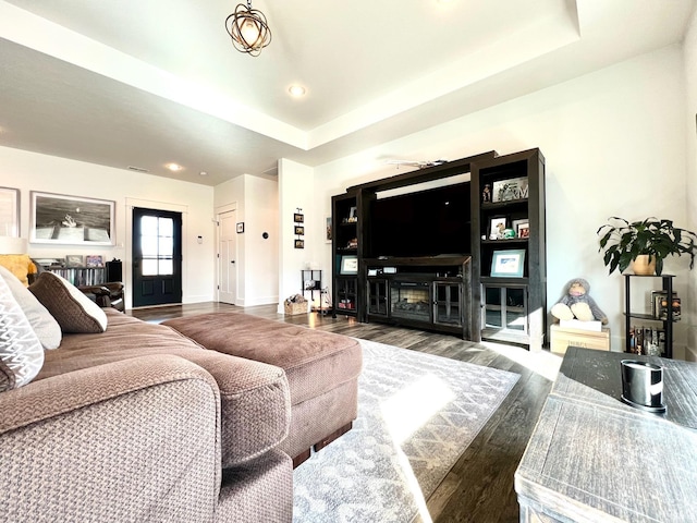 living area with visible vents, a raised ceiling, wood finished floors, a fireplace, and baseboards