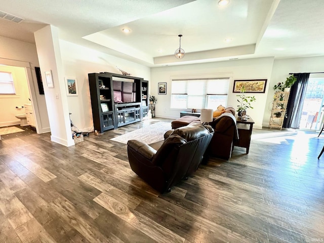 living area with visible vents, baseboards, recessed lighting, wood finished floors, and a raised ceiling