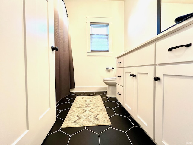 bathroom with baseboards, toilet, and tile patterned flooring