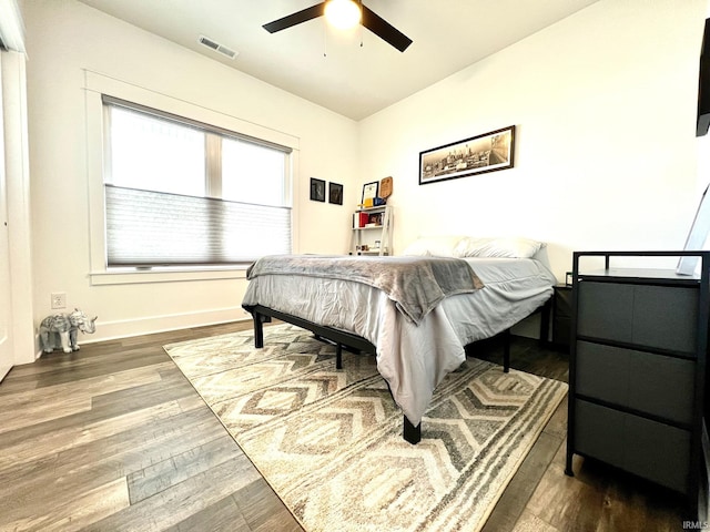 bedroom with visible vents, baseboards, ceiling fan, and wood finished floors