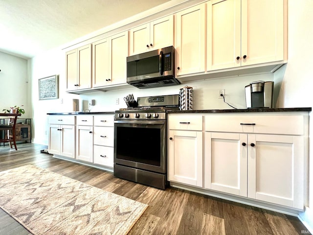 kitchen with dark countertops, appliances with stainless steel finishes, and dark wood finished floors