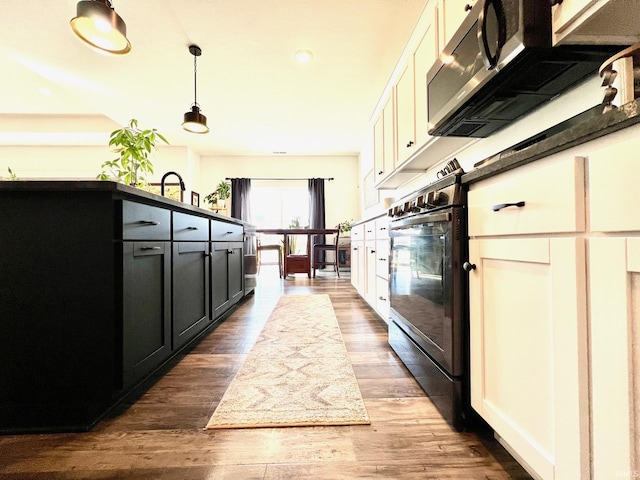 kitchen with dark wood finished floors, dark cabinetry, decorative light fixtures, and oven