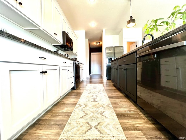 kitchen with light wood-style flooring, white cabinets, dishwasher, decorative light fixtures, and stainless steel fridge