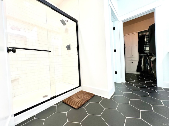 bathroom with tile patterned floors, baseboards, a spacious closet, and a shower stall