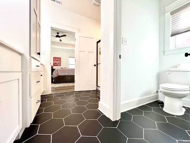 bathroom with visible vents, toilet, ensuite bathroom, baseboards, and ceiling fan