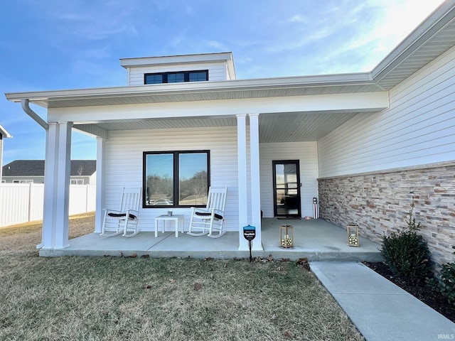 property entrance featuring a porch and fence