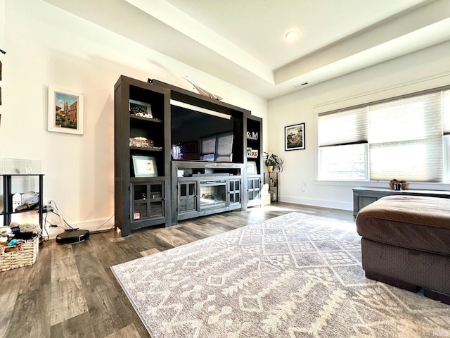 living area featuring wood finished floors, visible vents, baseboards, a tray ceiling, and recessed lighting