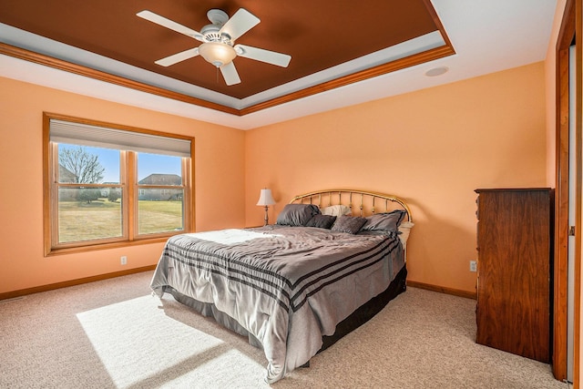 carpeted bedroom featuring crown molding, a ceiling fan, a raised ceiling, and baseboards