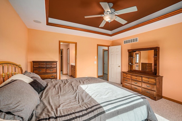 carpeted bedroom with a ceiling fan, a tray ceiling, baseboards, and visible vents