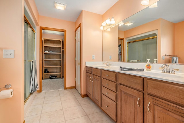 full bath with double vanity, a shower with shower door, tile patterned floors, and a sink