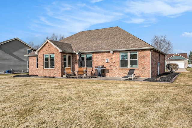 back of house with brick siding, a yard, a patio, and roof with shingles