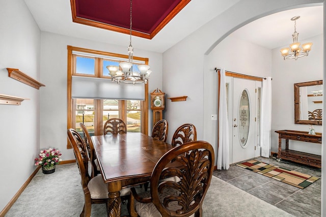 dining room with arched walkways, baseboards, a tray ceiling, and an inviting chandelier