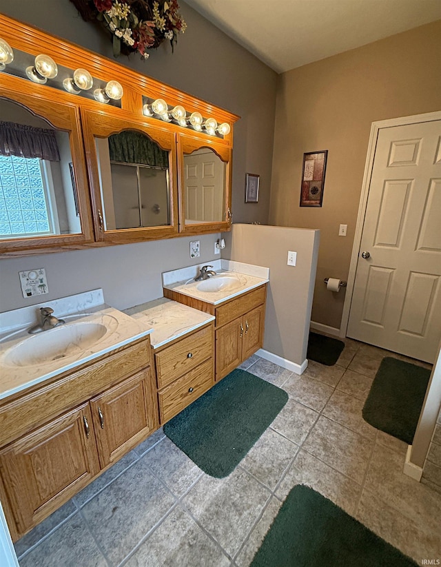 bathroom with double vanity, tile patterned floors, baseboards, and a sink