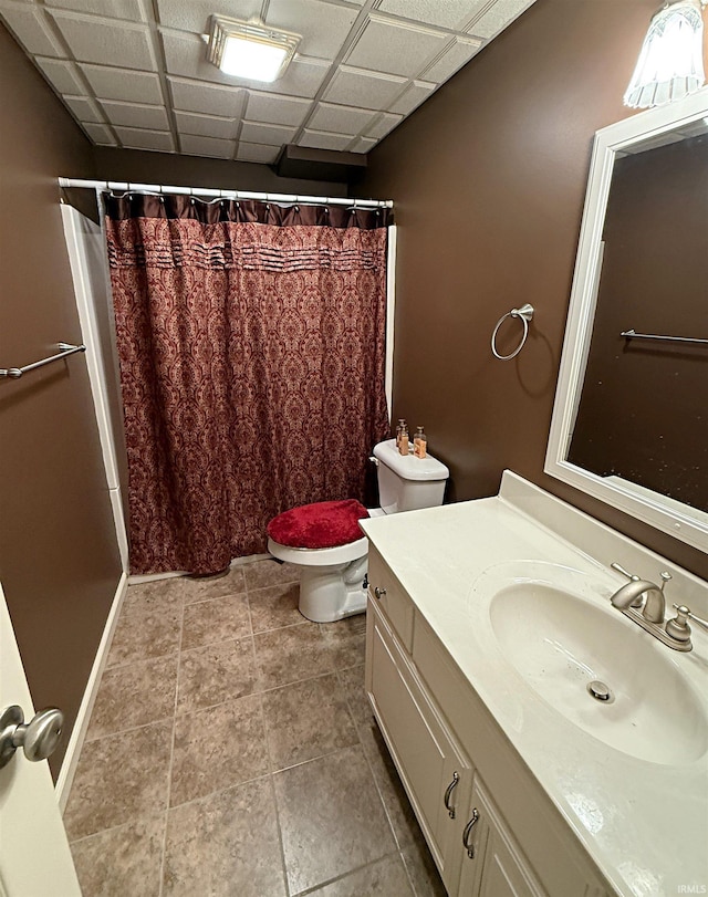 bathroom with a shower with shower curtain, toilet, and a paneled ceiling