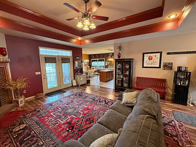 living area featuring ornamental molding, baseboards, a tray ceiling, and wood finished floors