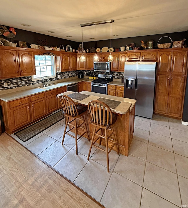 kitchen with a sink, stainless steel appliances, backsplash, and brown cabinetry