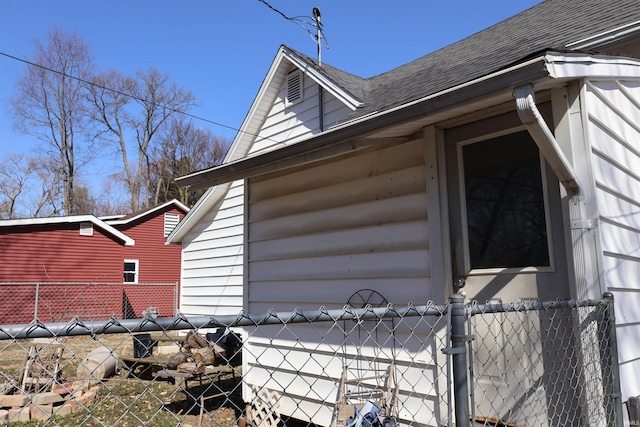 view of side of property with fence and a shingled roof