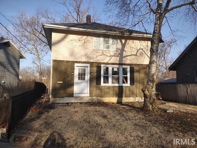 back of house with a chimney and fence