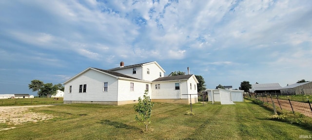 back of house with fence, crawl space, a yard, an outbuilding, and a storage unit