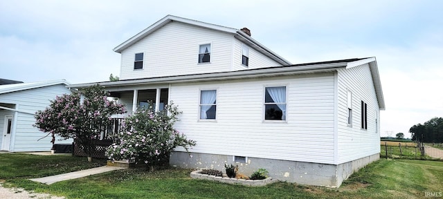 view of home's exterior featuring a porch, a yard, and a chimney