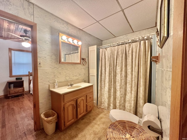 bathroom featuring vanity, a shower with curtain, a ceiling fan, a drop ceiling, and toilet