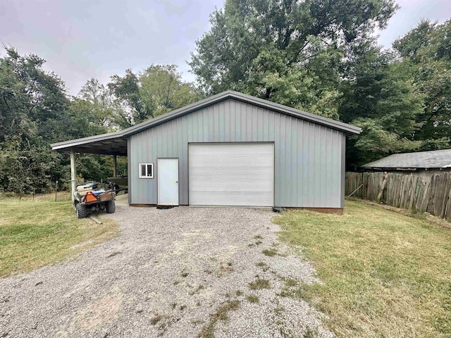 garage with a garage, driveway, and fence