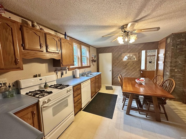 kitchen with white appliances, light floors, brown cabinets, and a sink