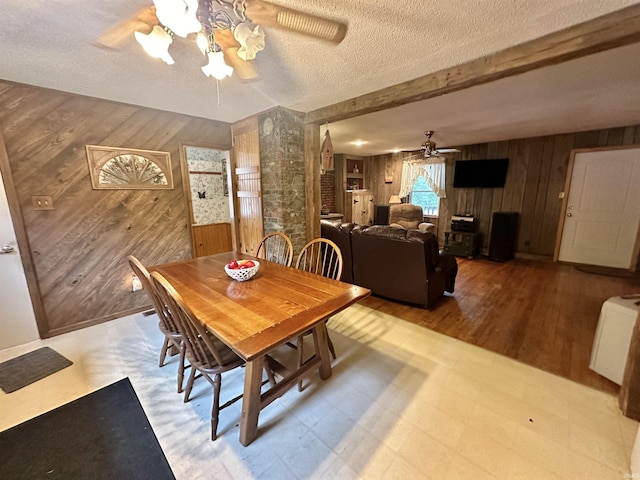 dining space featuring tile patterned floors, a textured ceiling, ceiling fan, and wooden walls