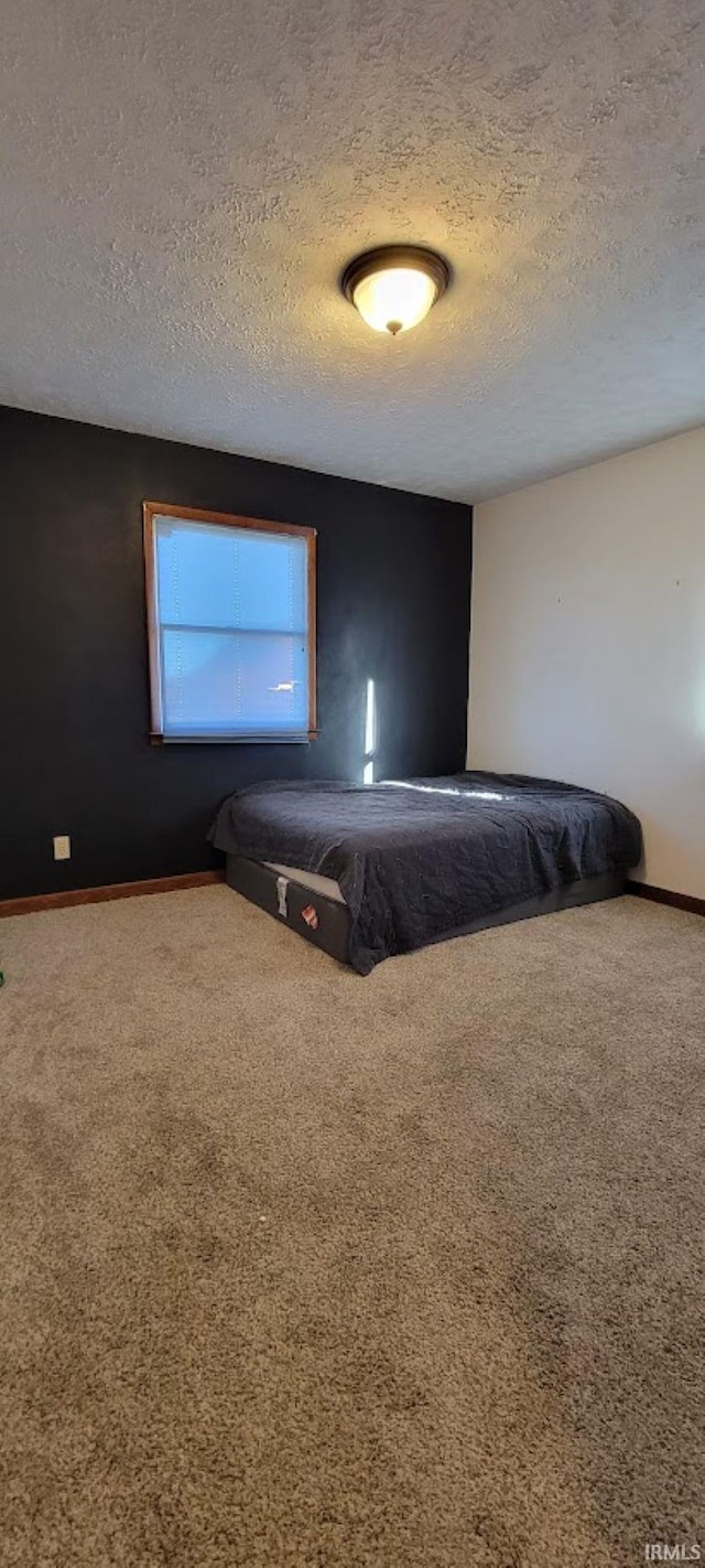 unfurnished bedroom with carpet flooring, a textured ceiling, and baseboards