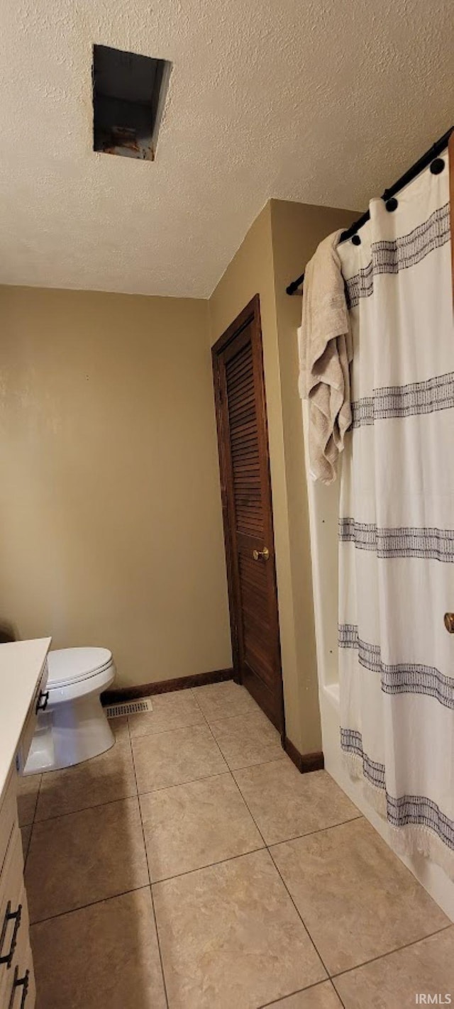 bathroom with tile patterned floors, a shower with curtain, toilet, a textured ceiling, and vanity