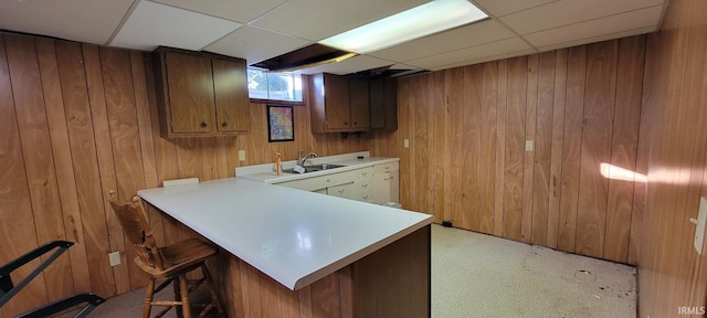 bar with a sink, a drop ceiling, and wood walls