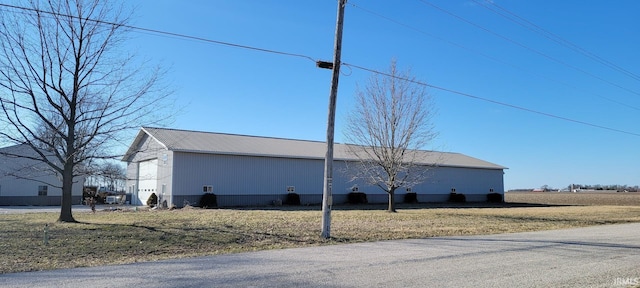 view of side of home with metal roof, an outdoor structure, and a pole building