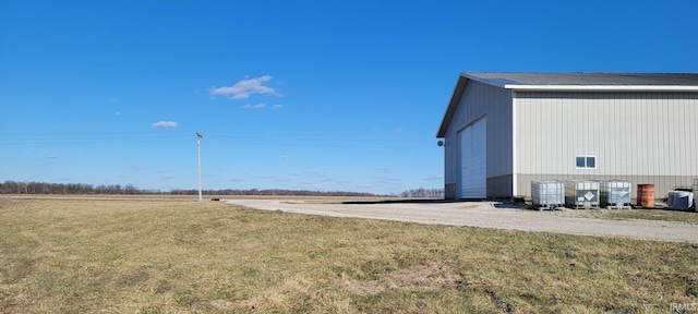 view of yard featuring a garage, central AC, and an outdoor structure