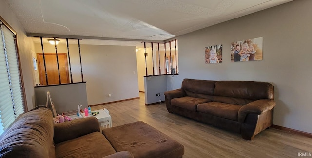 living area featuring a textured ceiling, baseboards, and wood finished floors