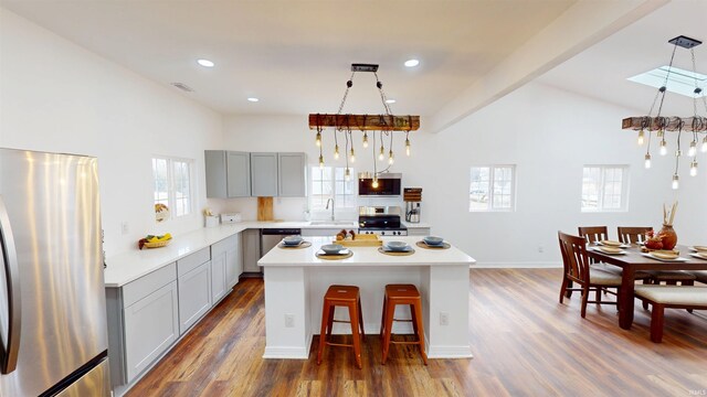 kitchen featuring dark wood-type flooring, a breakfast bar area, light countertops, appliances with stainless steel finishes, and a sink