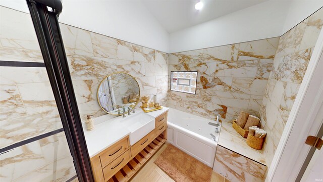 bathroom with vanity, lofted ceiling, a bath, and tile walls