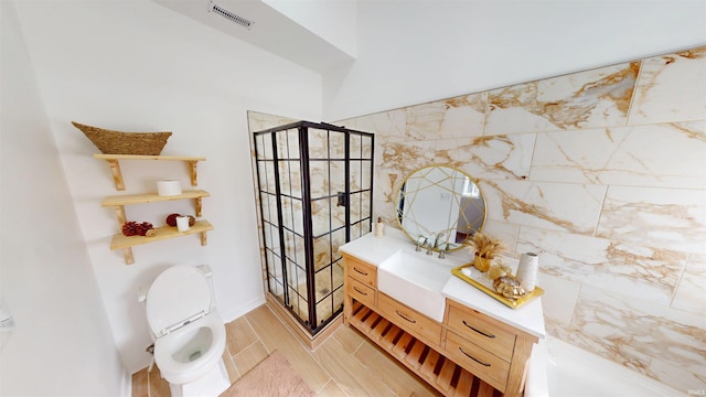 bathroom with visible vents, toilet, vanity, and walk in shower