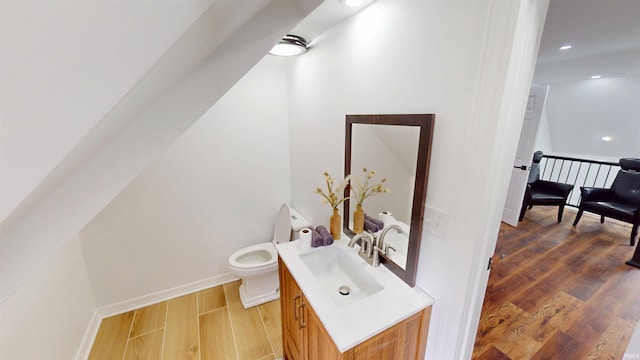 bathroom featuring toilet, wood finished floors, recessed lighting, baseboards, and vanity