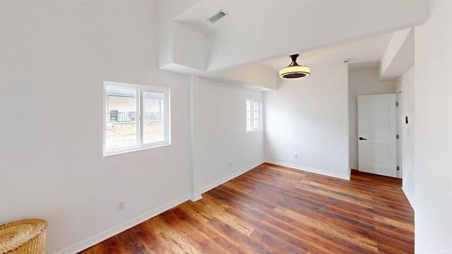 spare room featuring wood finished floors, visible vents, and baseboards