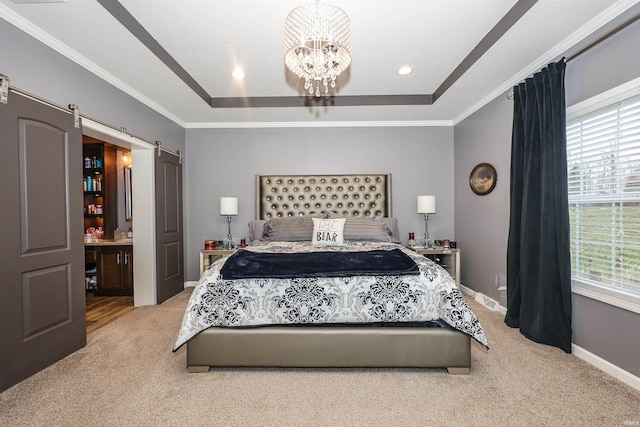 bedroom with baseboards, a tray ceiling, crown molding, a barn door, and carpet flooring